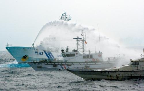 臺灣“海巡署”的巡邏船（中）在掩護(hù)保釣船“全家福”號（右）躲避日本海上保安廳巡視船的水炮攻擊,。