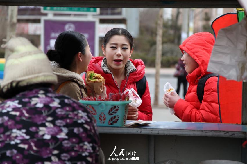 2014年2月17日,，山東濱州,，背著大包小包的藝考考生在濱州學(xué)院考點外買飯。