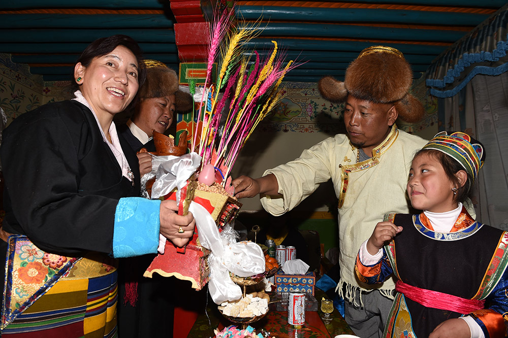 2月27日,，拉薩市城關(guān)區(qū)阿壩林卡社區(qū)居民央拉（左）向鄰居敬獻(xiàn)“切瑪”,。